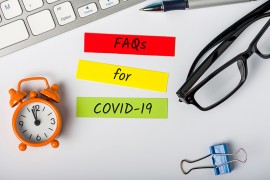 Fragen und Antworten zum Versicherungsschutz während Corona Tastatur, Kugelschreiber, Post-its auf Bürotisch