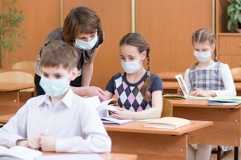 Schüler*innen und Lehrerin im Klassenraum Schüler*innen und Lehrerin mit Mund- und Nasenschutz im Klassenraum